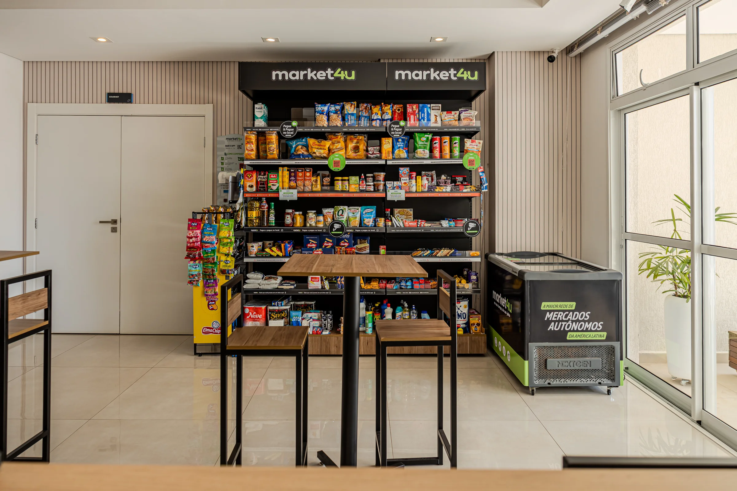 Minimercado com bebidas, lanches, mesas e cadeiras.